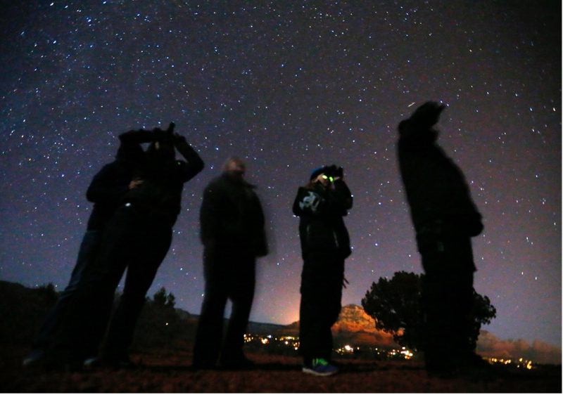 Người ta sử dụng kính nhìn trong bóng tối để chiêm ngắm bầu trời đêm trong một tour du lịch Vật Thể Bay Không Xác Định (UFO) ở sa mạc bên ngoài Sedona, tiểu bang Arizona, hình chụp tư liệu ngày 14/02/2013. Cùng với việc phát hành báo cáo được mong đợi trong tháng này của Bộ Quốc Phòng Mỹ về hiện tượng không xác định ngoài không gian, hãng tin Công giáo Catholic News Service (CNS) nói chuyện với ba chuyên gia về khả năng khám phá ra sự sống ngoài trái đất và những liên hệ thần học của nó (CNS photo/Mike Blake, Reuters).